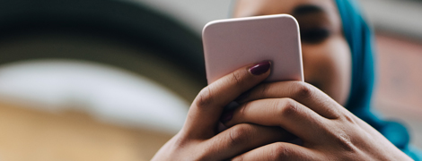 A woman typing phone number on her cell phone to call to schedule an appointment.