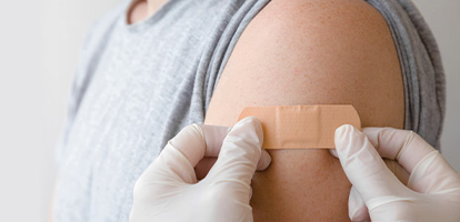 AHN nurse putting a bandage on a woman's shoulder after getting the flu shot.