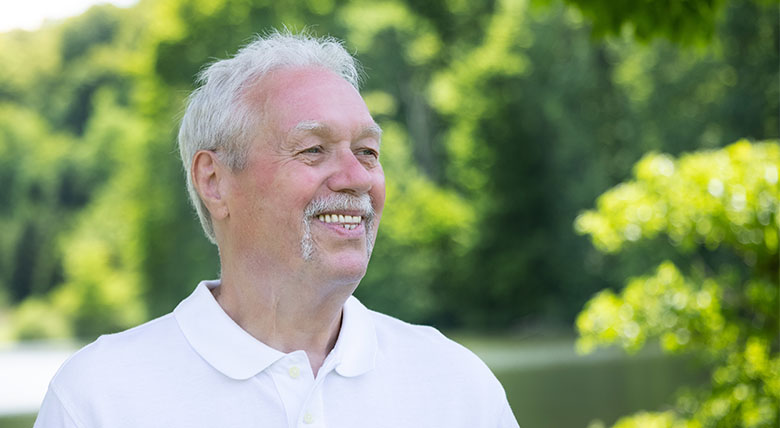 man smiling at the camera as his photo is taken outdoors