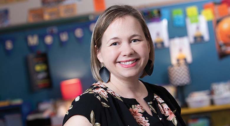 Cancer survivor, AHN patient, and teacher KD Meucci smiling at the camera as her photo is taken in her classroom.